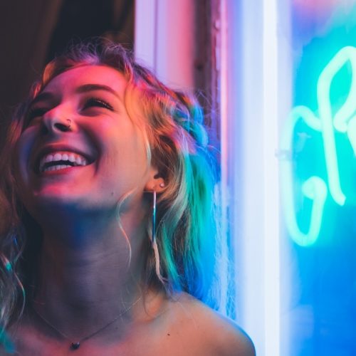 happy woman by neon sign